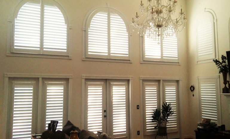 Television room in open concept Chicago home with plantation shutters on tall windows.