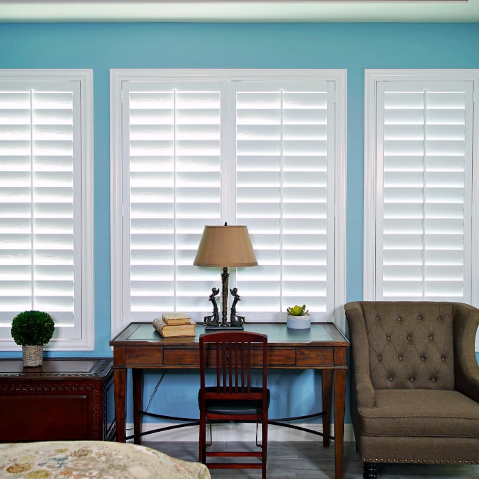 White plantation shutters next to blue walls