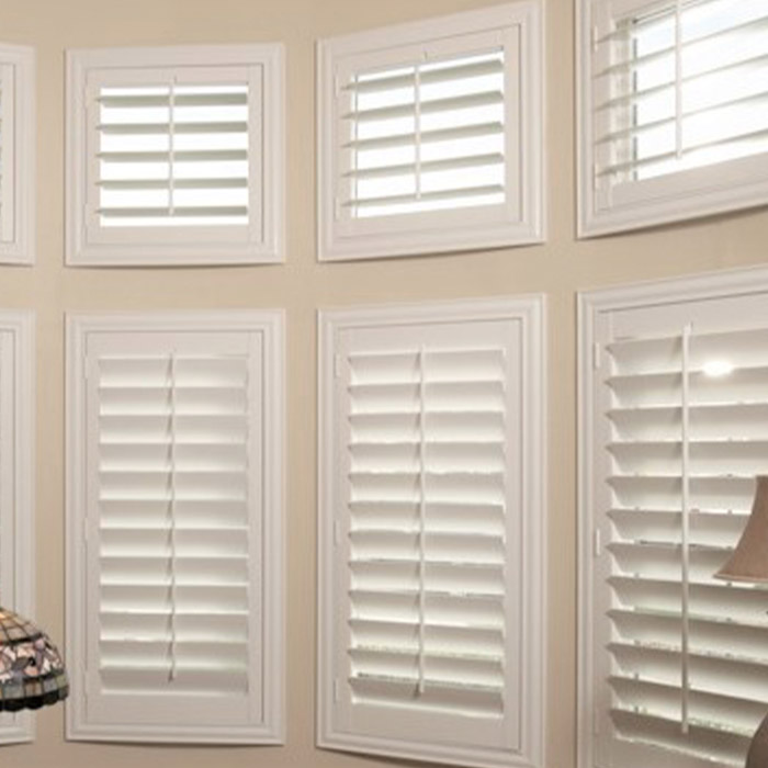 White eyebrow shutters in a bay window style within a living room.