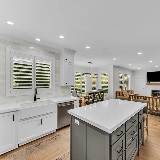 White Polywood shutters in an open concept area of the kitchen and living room