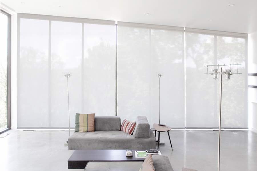Motorized window shades make controlling natural light effortless in your Chicago great room. White motorized shades on a wall of tall great room windows