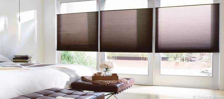 Minimal Chicago bedroom with high ceiling windows and brown cellular shades.