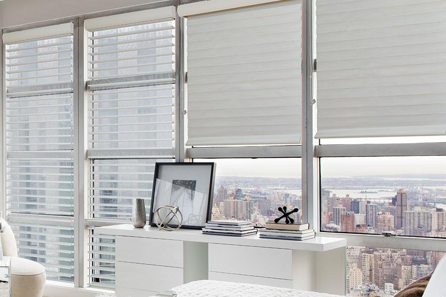 White sheer shades on a wall of windows in a white bedroom