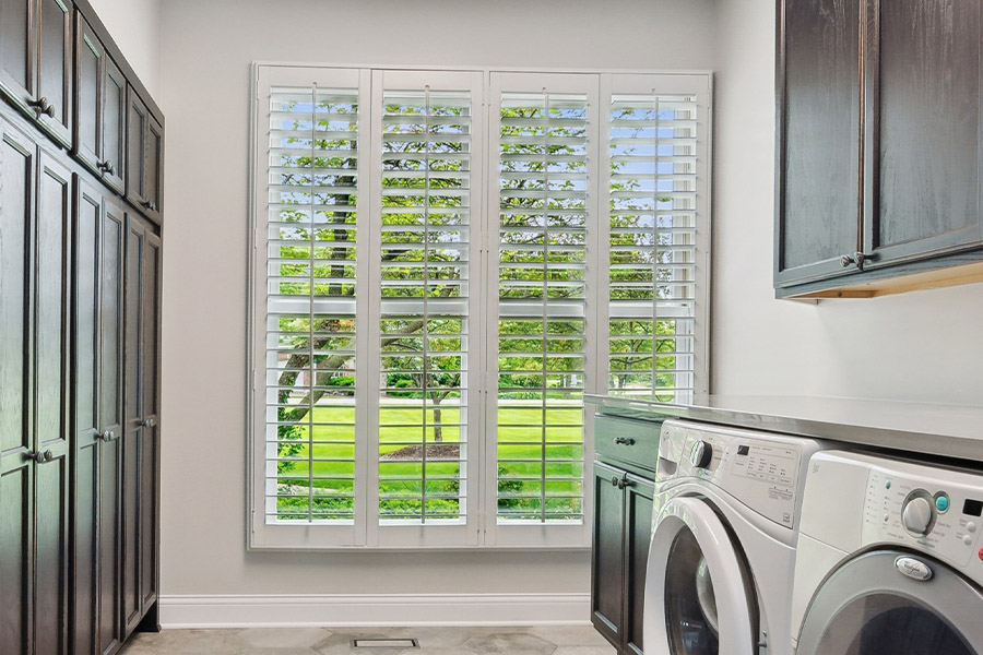 Find the perfect level of natural light for your Chicago laundry room with interior shutters. White Polywood shutters letting light through a laundry room window