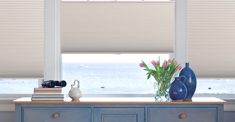 Cellular shades come in a variety of options, and with zero cords. Blue dresser with shades above