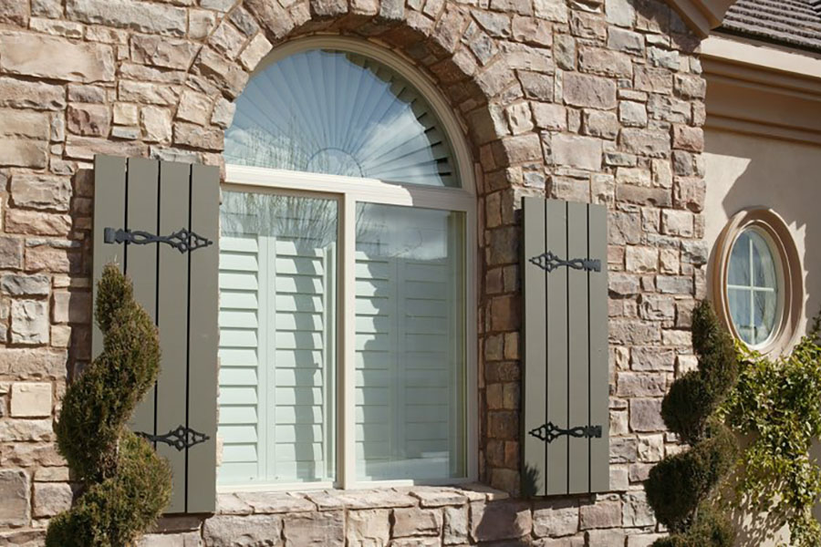 Interior shutters block annoying outside noise and give your home more curb appeal. Exterior view of white Polywood shutters on a front window