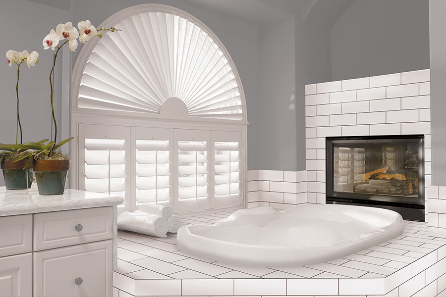 Explore our selection of window treatments for builders in Chicago to find the perfect ones for your next construction project. White Polywood shutters on an arched bathroom window