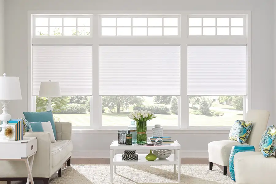 Insulating cellular shades can help keep cold air and hot UV rays from entering your Chicago home. White cellular shades on windows in a white living room